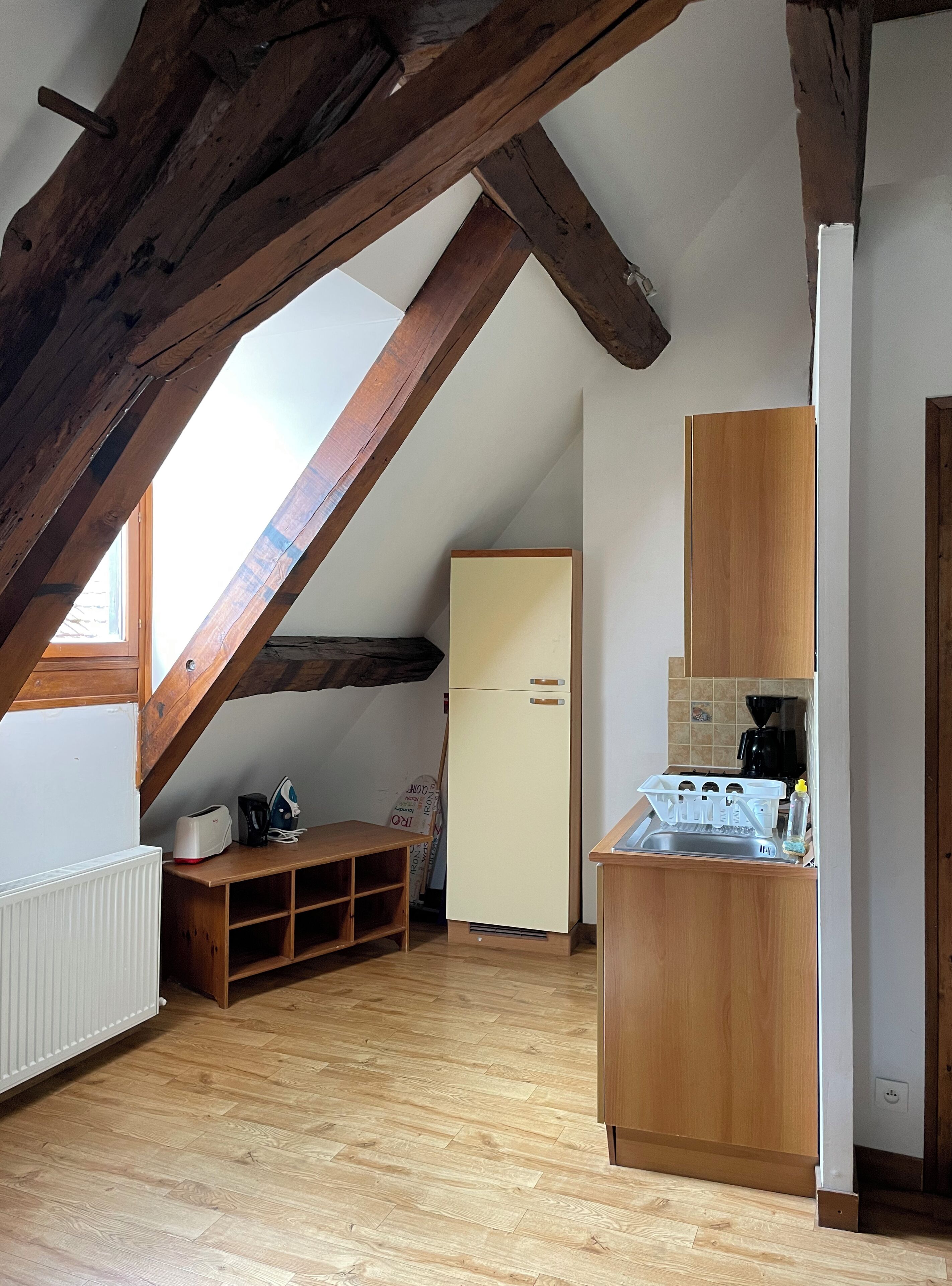 Une petite cuisine avec des poutres en bois, un réfrigérateur blanc, un meuble en bois et une table en bois.