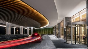 Un edificio moderno con techo curvo, entrada de vidrio y un camino pavimentado.