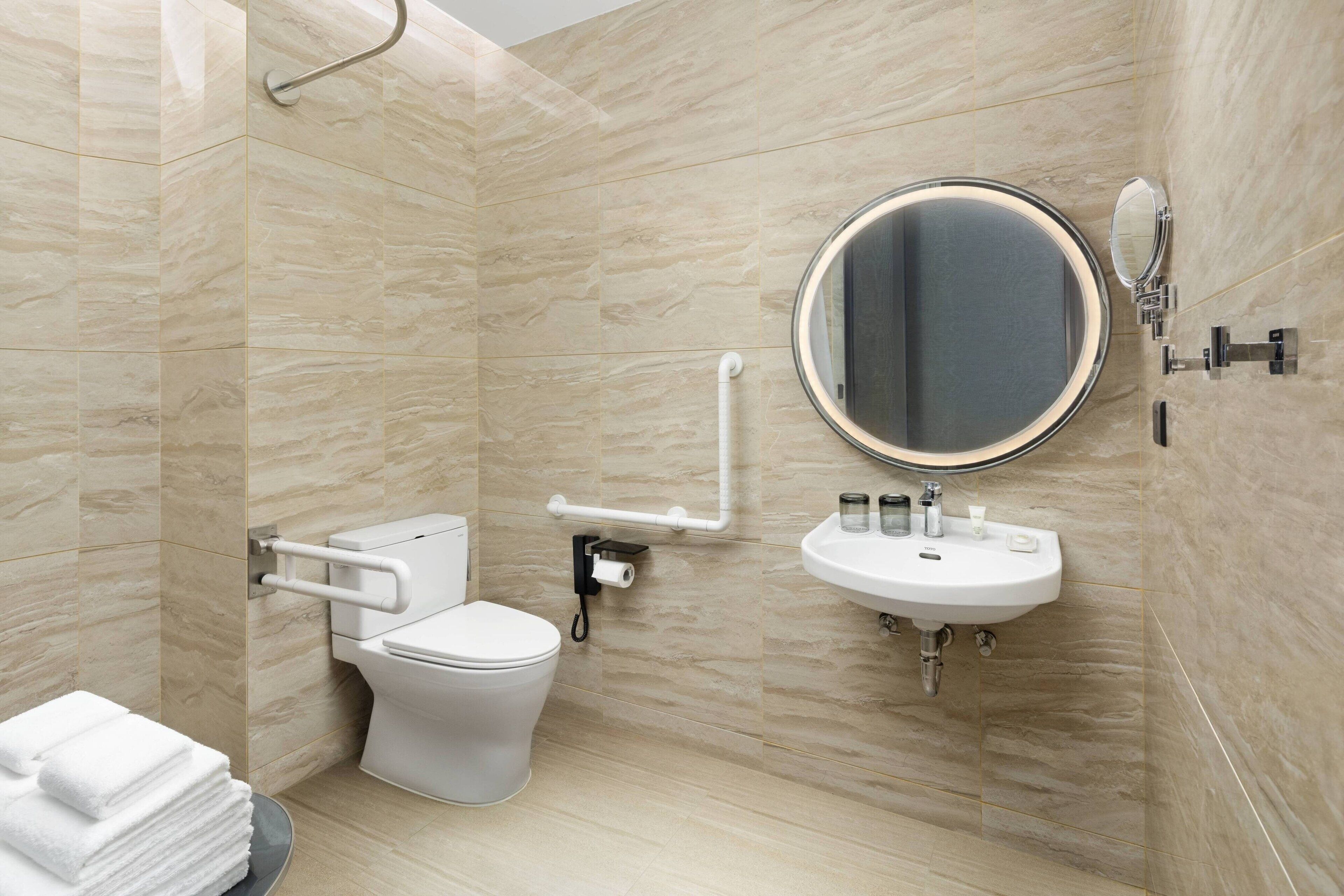 Un baño moderno con inodoro, lavamanos y espejo.
