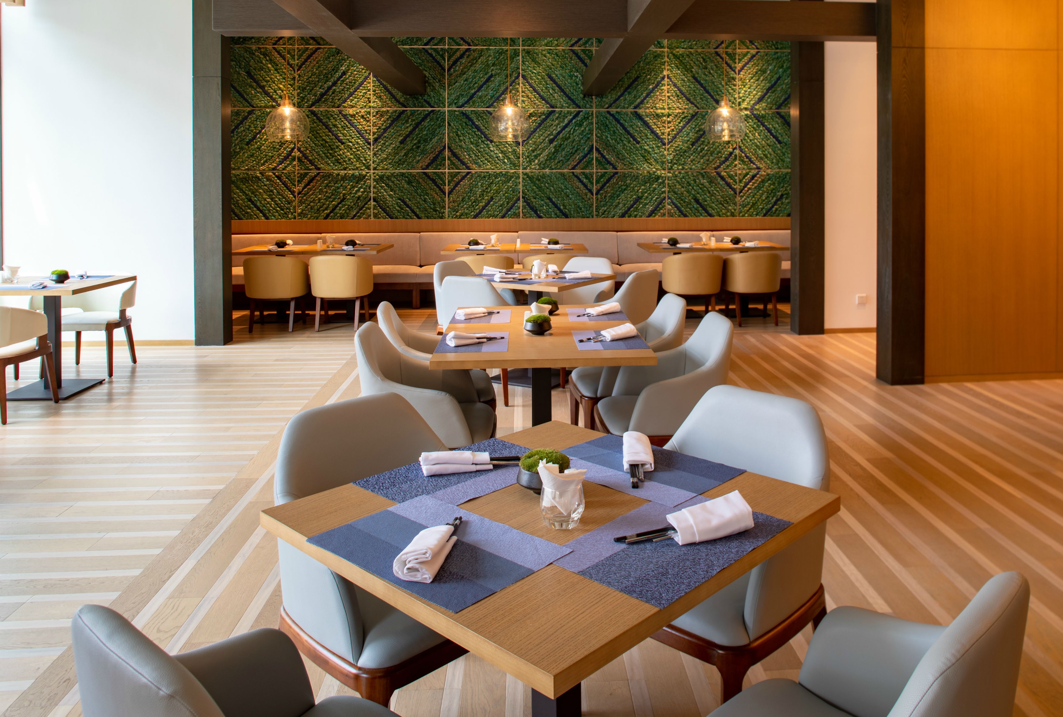 A modern dining area with a geometric patterned wall, wooden flooring, and contemporary furniture.
