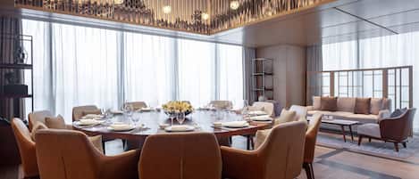 A modern dining area with a large round table set for six, surrounded by leather chairs.
