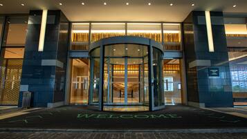 A hotel entrance with a revolving door, a welcome mat, and a sign indicating the name 'Courtyard Marriott'.
