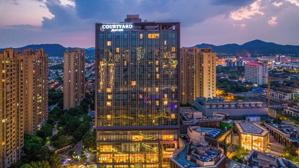 Un hotel de gran altura con fachada de vidrio moderna, varios pisos y señalización destacada en la parte superior.