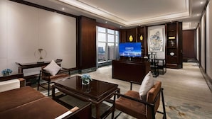 Un moderno vestíbulo de hotel con un televisor grande, asientos cómodos y vistas a la ciudad.