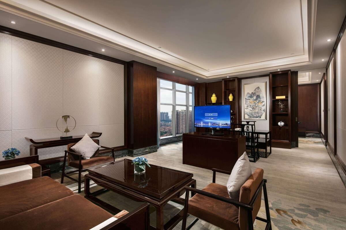 Un vestíbul d'hotel modern amb un televisor gran, seients confortables i vista a la ciutat.