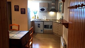 A compact kitchen with wooden cabinets, a built-in oven, and a dishwasher. - Apartamentos  Sherpa (Pas de la Casa)