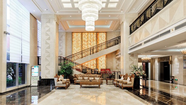 A spacious lobby with a grand staircase, a chandelier, and a reception desk. - Wyndham Garden Wuhan West (Wuhan)