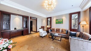 A spacious living room with a chandelier, a sofa, a coffee table, and a cabinet with glass doors. - Wyndham Garden Wuhan West (Wuhan)