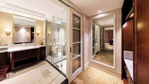 A modern bathroom with a glass shower enclosure, a vanity with a mirror, and a walk-in closet with sliding doors. - Wyndham Garden Wuhan West (Wuhan)
