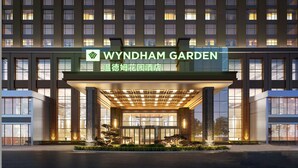 A hotel entrance with a covered walkway, large windows, and a sign reading "WYNDHAM GARDEN". - Wyndham Garden Wuhan West (Wuhan)