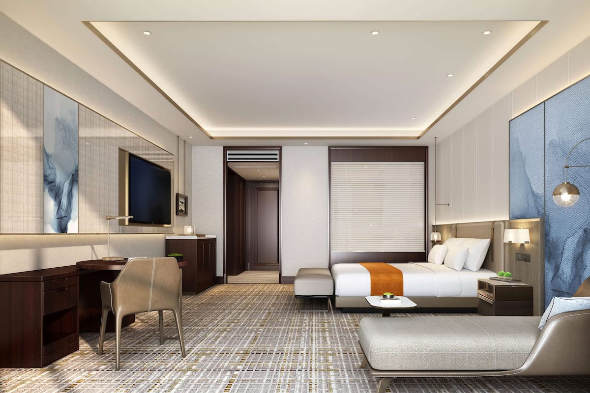 Una habitación de hotel moderna con una cama grande, un escritorio, una silla y un televisor.