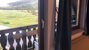 A balcony with a view of a grassy field and trees. - Sporthostel Rössle (Schluchsee)