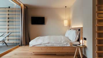 Un dormitorio con una cama de madera, una mesita de noche, un televisor y un ventanal con persianas.