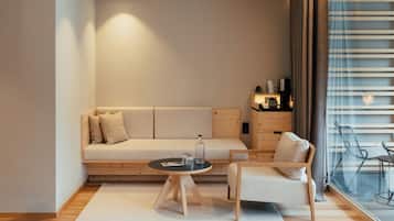 Een moderne woonkamer met een bank, een klein rond tafeltje, een stoel en uitzicht door een raam met gordijnen.