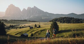 A mountainous landscape with a small cabin and a couple walking.