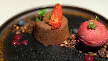 A dessert with chocolate mousse, strawberries, and a scoop of red ice cream on a plate.
