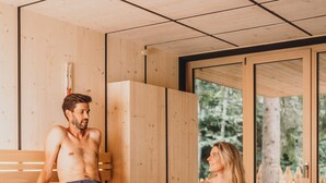A sauna with wooden benches and a large window. - Sensoria Dolomites (Castelrotto)