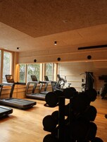 Un gimnasio con cintas de correr, elípticas y equipo de levantamiento de pesas.
