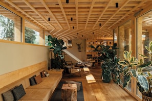 A modern interior with a wooden ceiling, large windows, a sofa, chairs, and a bookshelf. - Sensoria Dolomites (Castelrotto)