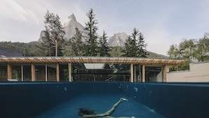 An indoor swimming pool with a view of mountains in the background. - Sensoria Dolomites (Castelrotto)
