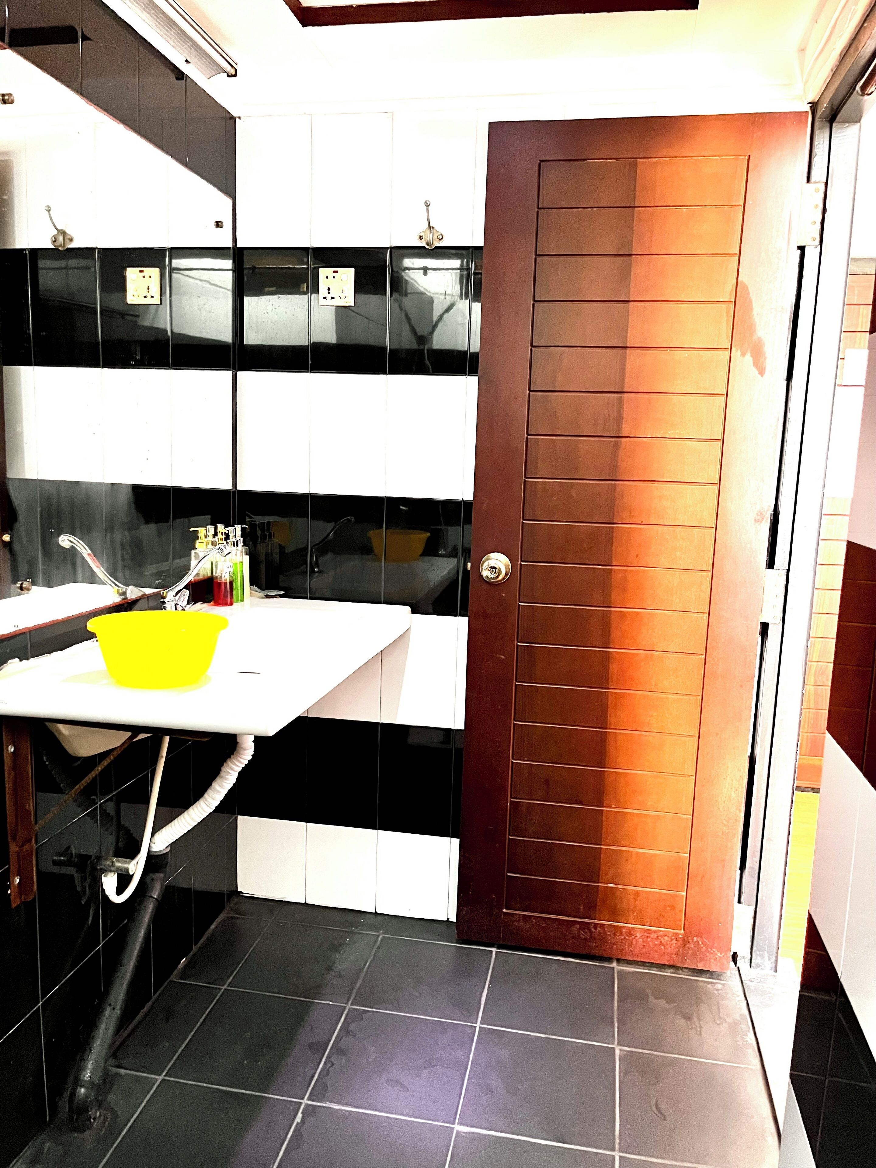 Cocina pequeña con un lavamanos, un tazón amarillo y un armario con artículos de aseo.