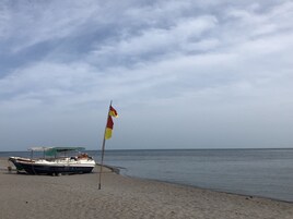 A boat on a sandy beach with a flag in the foreground.