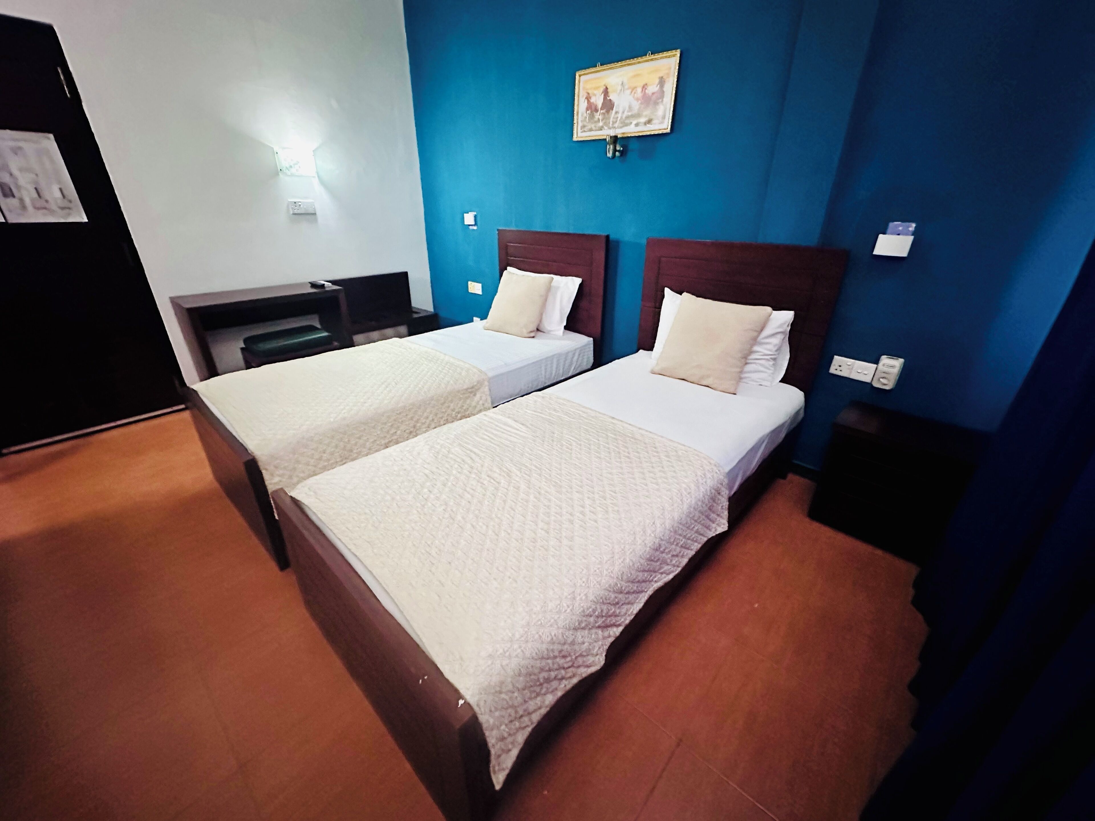 Une chambre d’hôtel avec deux lits, un bureau et un tableau accroché au mur.