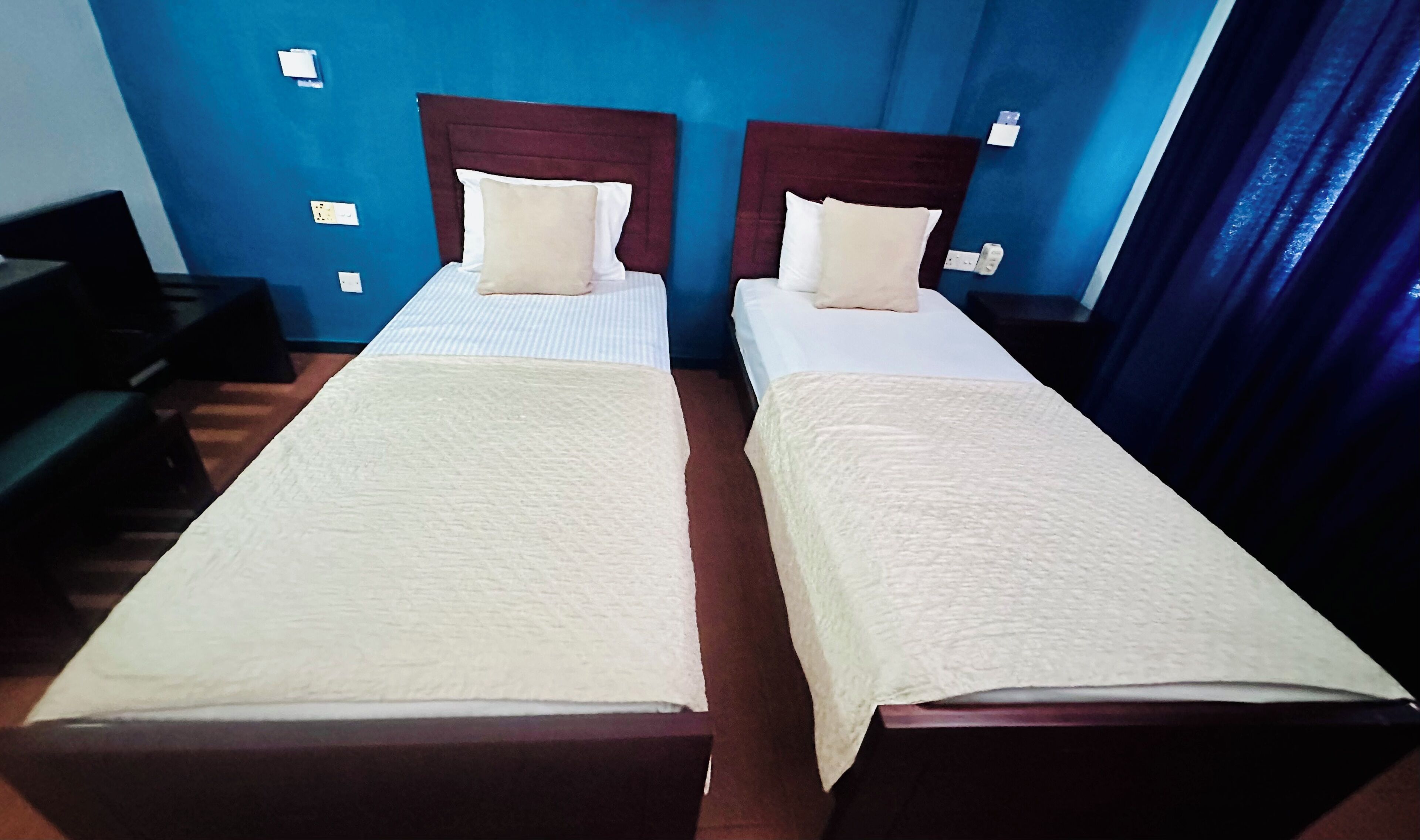 A hotel room with two single beds, each with a wooden headboard and white bedding.