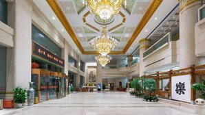 A spacious hotel lobby with a grand chandelier, multiple floors, and a traditional Asian architectural style.