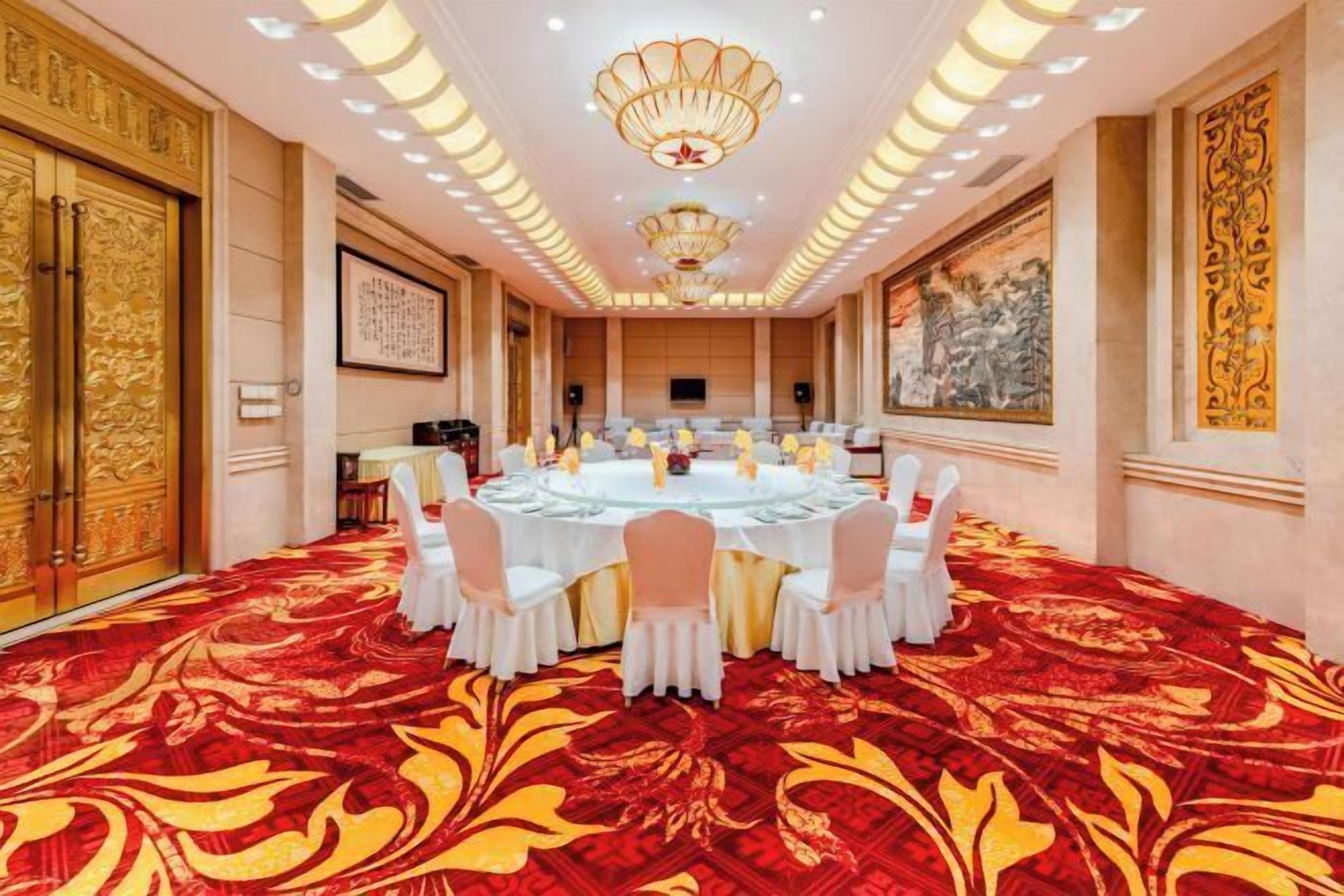 A conference room with a round table, white chairs, and a red carpet.