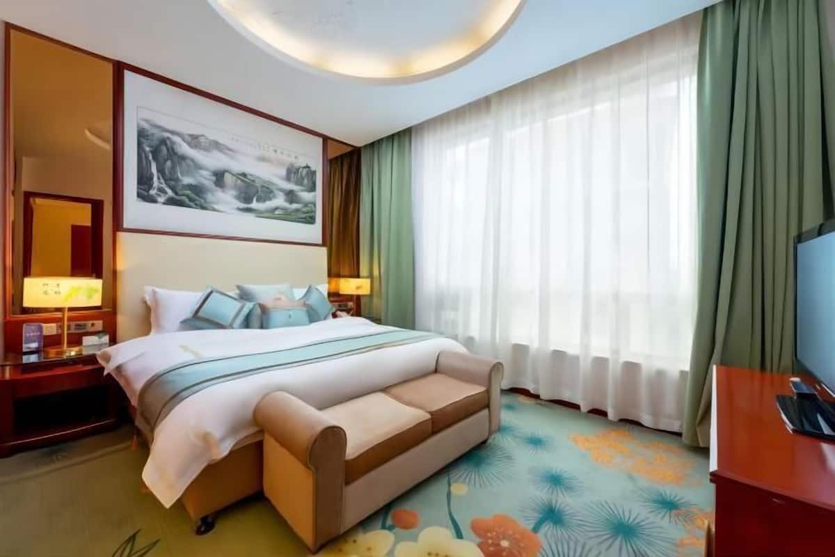 Ein Hotelzimmer mit einem Bett, einer Couch, einem Fernseher und einem Bild an der Wand.