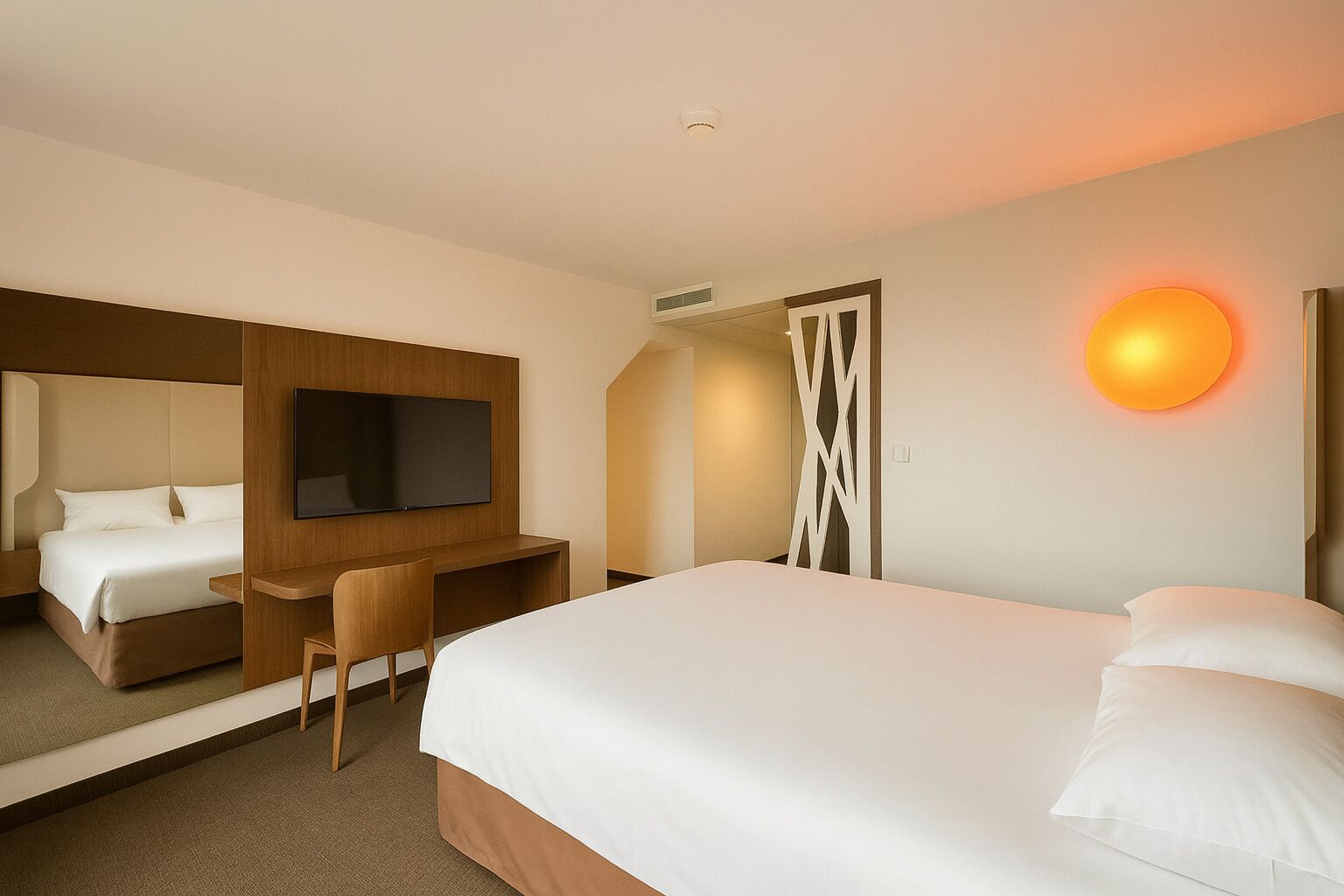 Habitación de hotel con cama, escritorio, silla, televisor y luz en la pared.