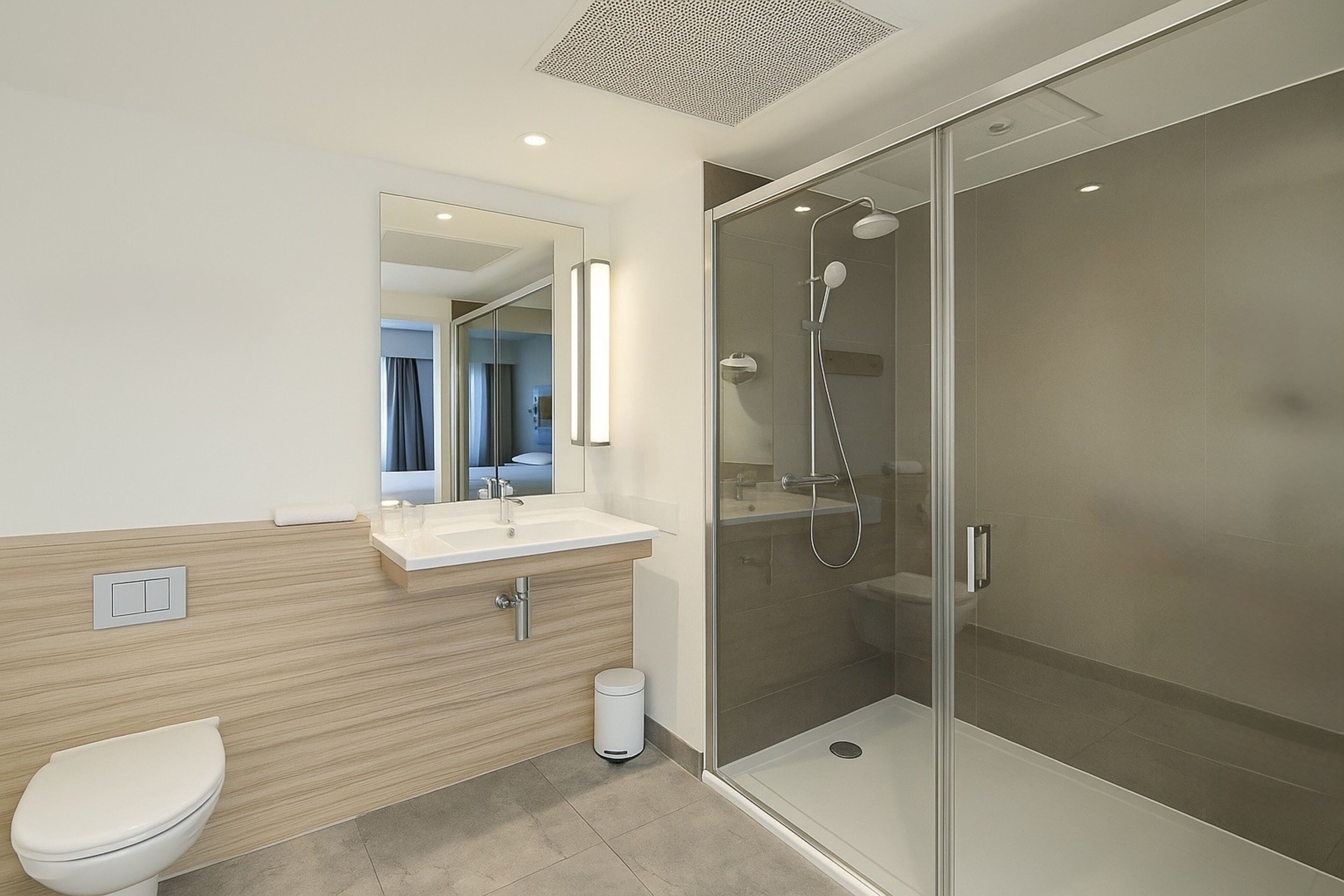A modern bathroom with a glass-enclosed shower, a white sink, and a toilet.