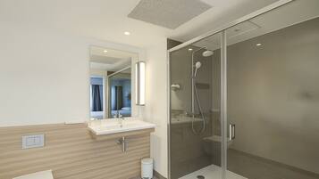 A modern bathroom with a glass-enclosed shower, a white sink, and a toilet.