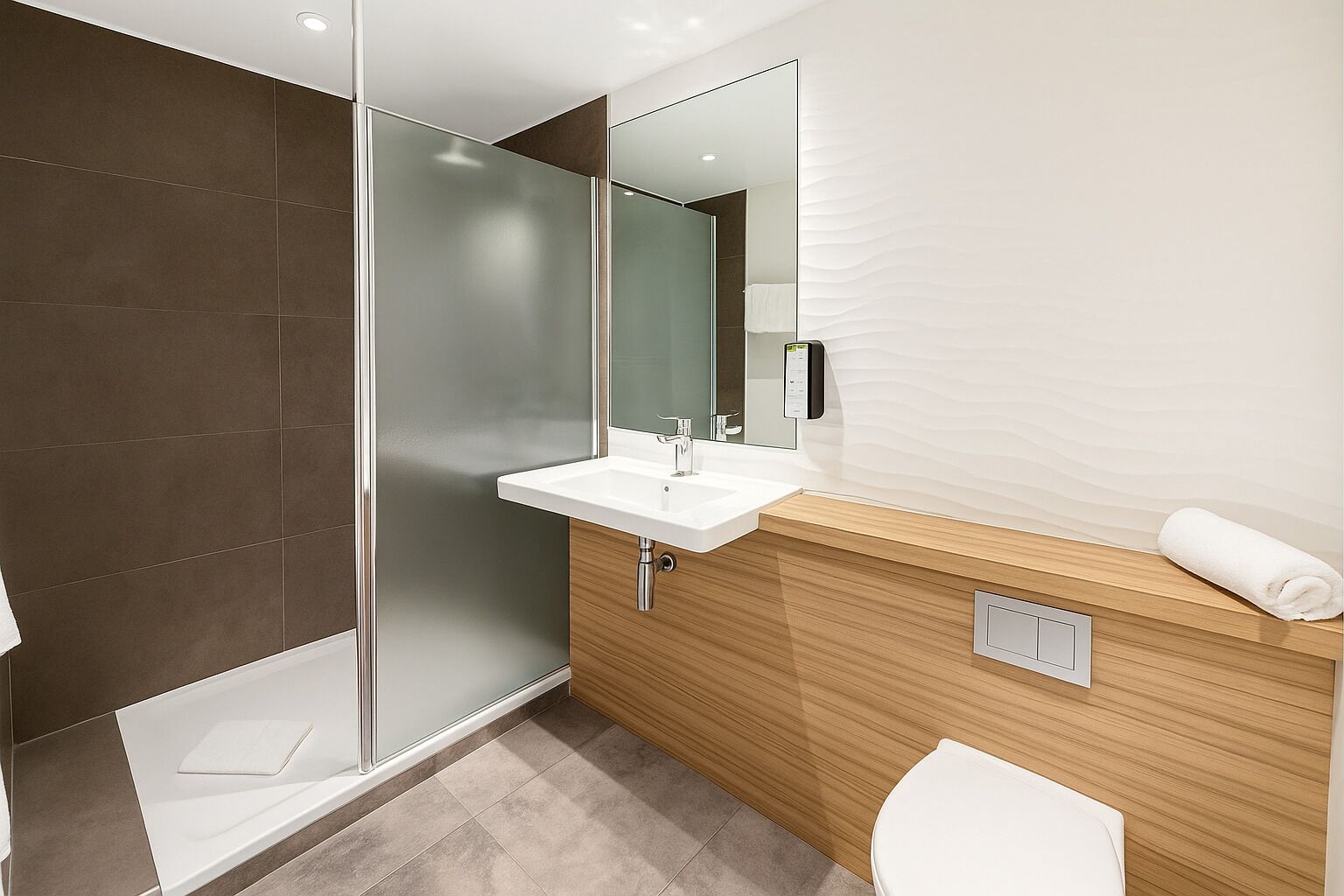 A modern bathroom with a glass shower enclosure, a white sink, and a wooden vanity.