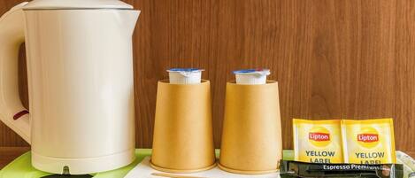 A white kettle, two brown paper cups, and two yellow Lipton tea packets on a green tray.