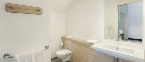 A modern bathroom with a wooden vanity, a toilet, and a towel rack.