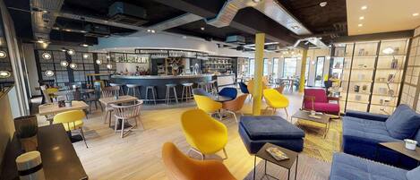 A modern lounge area with a bar, seating arrangements, and a bookshelf.