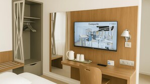 A hotel room with a bed, a desk with a chair, a TV mounted on the wall, a wardrobe, and a bedside table with a lamp. - Campanile Fontainebleau (Fontainebleau)