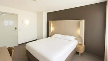 Habitación de hotel con una cama grande, mesitas de noche, un escritorio y una puerta con interruptor de luz.