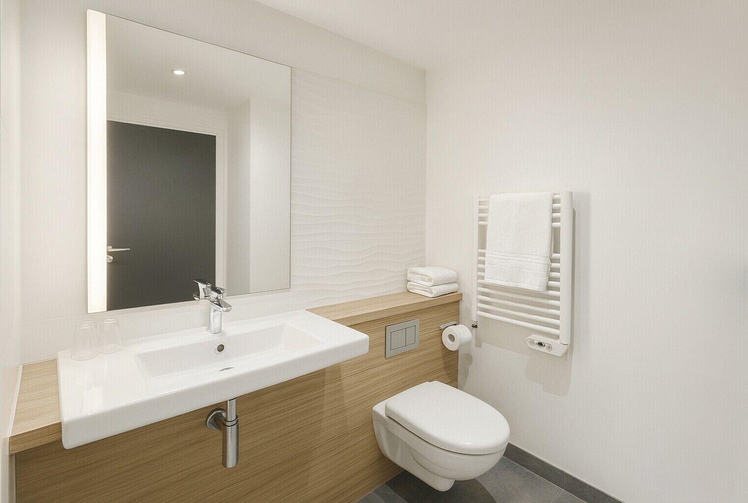 A bathroom with a white sink, mirror, toilet, and towel rack.