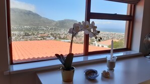A window with a view of a town and mountains, a potted plant, a candle, and a small dish. - A Place in Thyme (Cape Town)