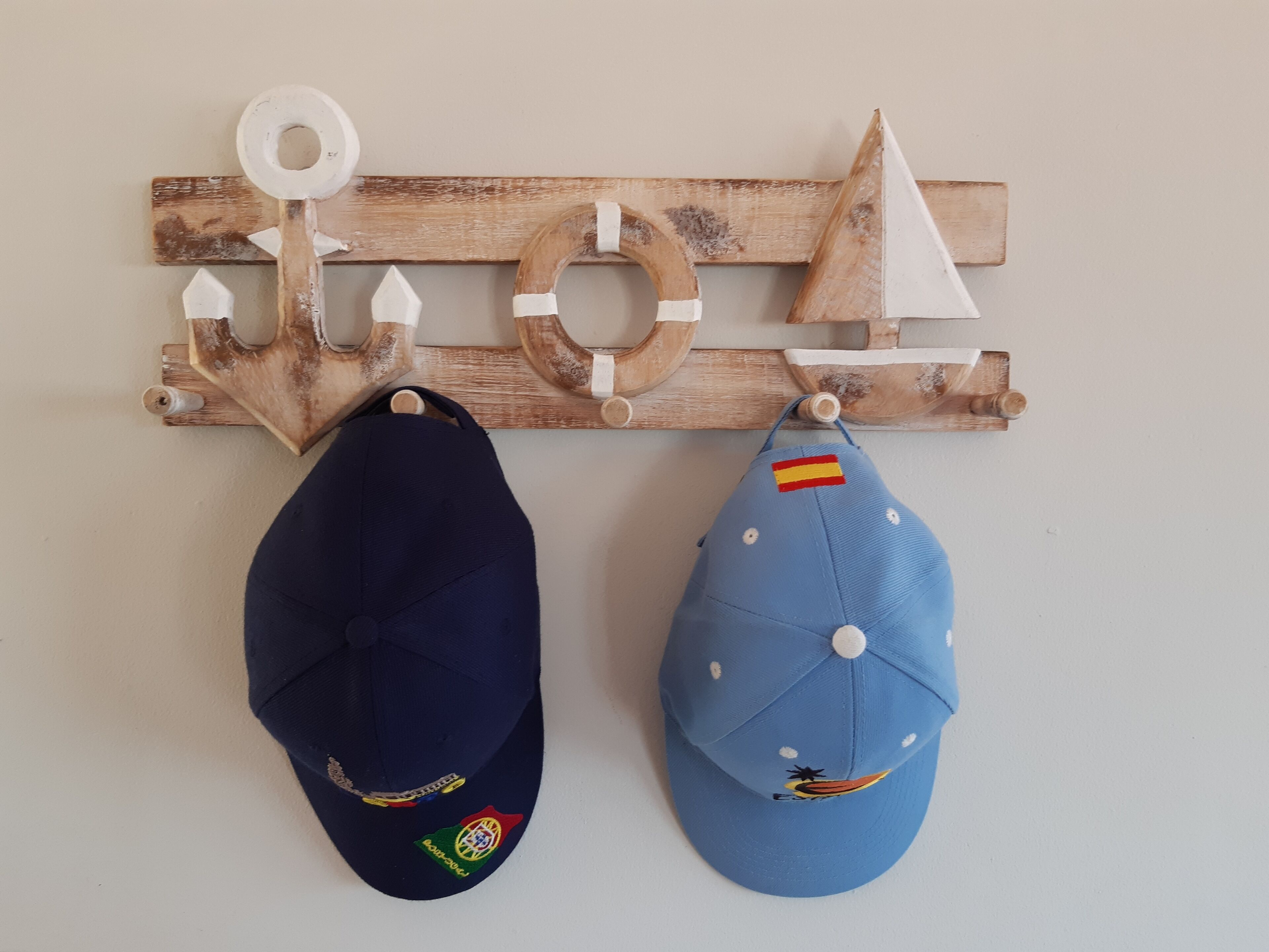 Dos gorres penjades en un penjador de fusta fixat a la paret.