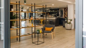 Een modern interieur met een bar, houten planken en een zithoek met een stoel en een tafel.