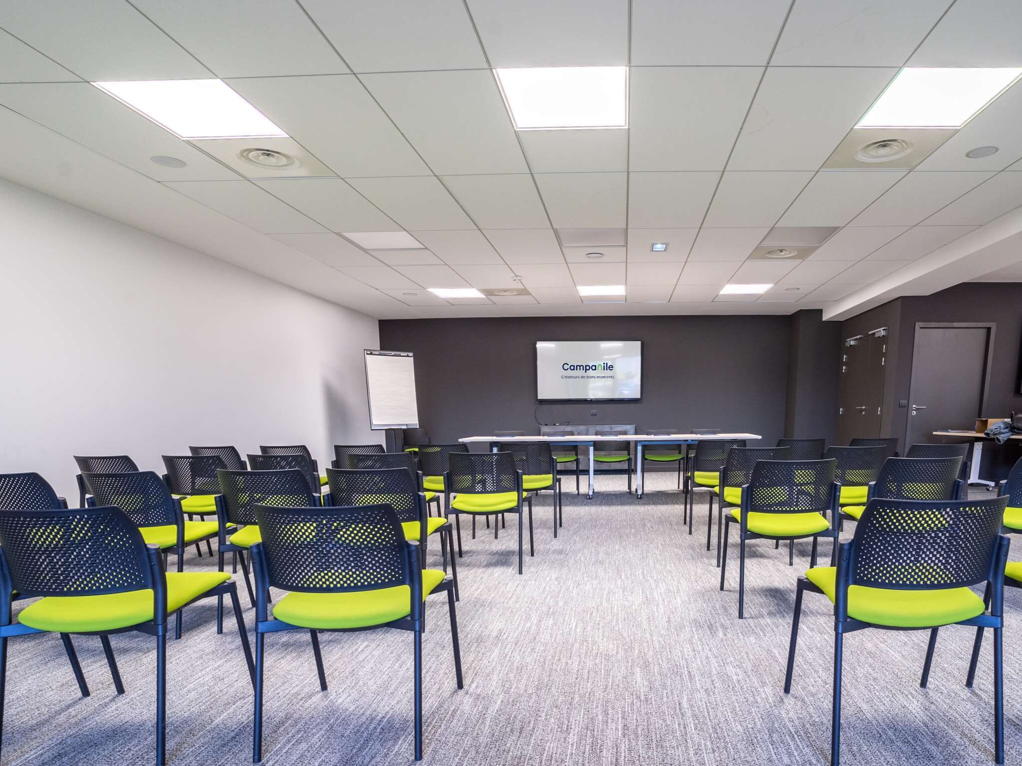 A conference room with a long table and chairs, a projector screen, and a whiteboard.
