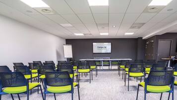 Un salón de conferencias con una larga mesa y sillas, una pantalla de proyector y una pizarra.