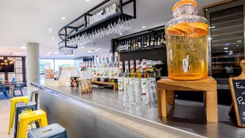 Una zona de bar con una jarra grande de cerveza, vasos y botellas de licor.