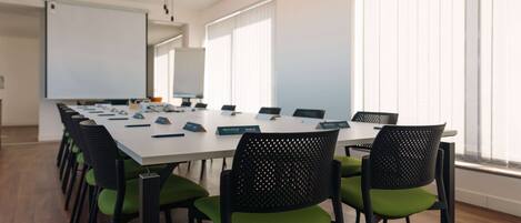 A conference room with a long table, multiple chairs, nameplates, and a whiteboard.