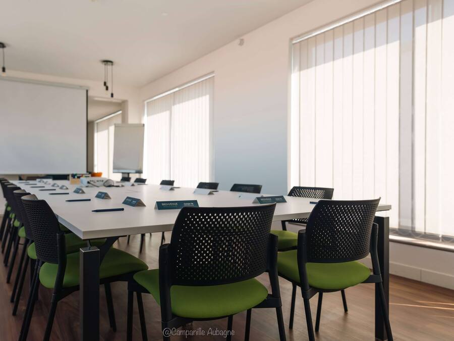 Een vergaderruimte met een lange tafel, meerdere stoelen, naamplaatjes en een whiteboard.