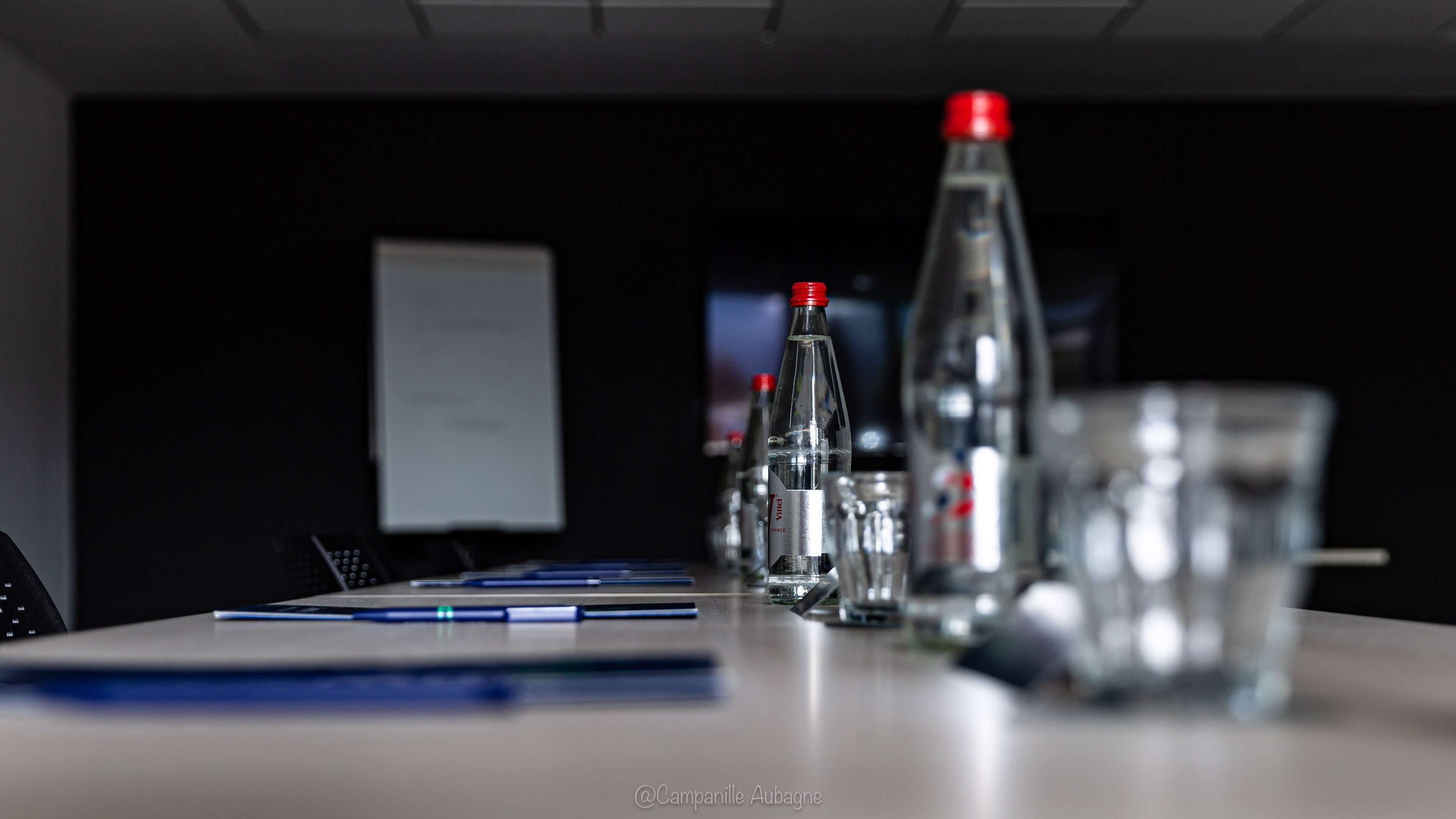 A conference table with water bottles and glasses, a whiteboard, and a laptop.